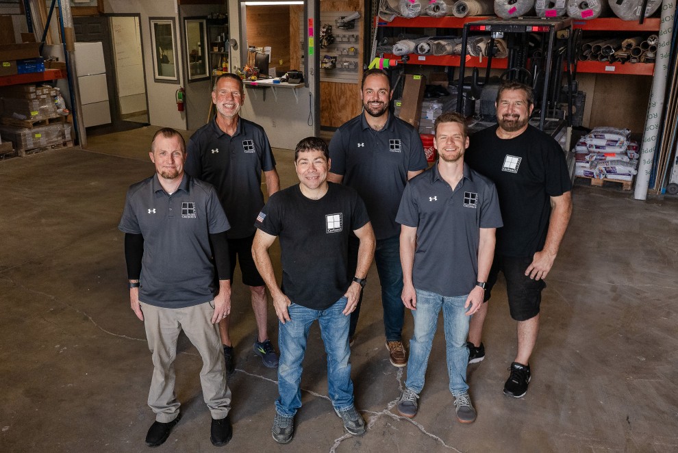 Carlson's Floors commercial team photo - group of professional installers and project managers in company polo shirts standing in warehouse